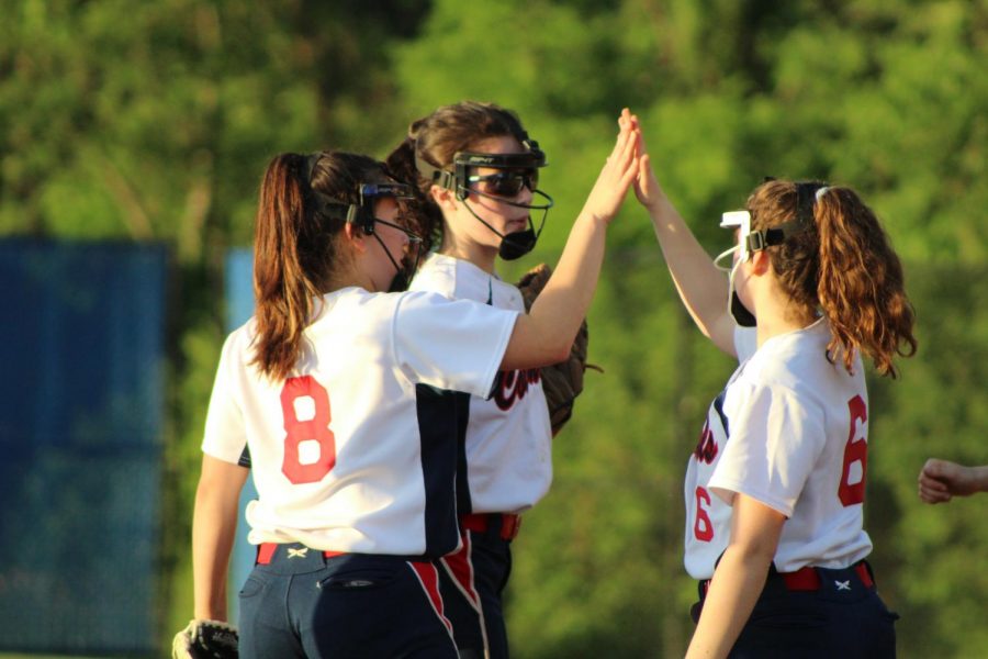 After preventing the runners on third and second from scoring additional runs on a sacrifice bunt attempt in the top of the third inning, sophomore Alexandra Friedman (right), senior Grace Stewart (middle), and freshman Michelle Boisvert (left) celebrate with a high-five before returning to their respective positions. 