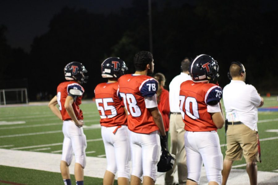 Standing on the sideline, a group of players intensely watch the game 