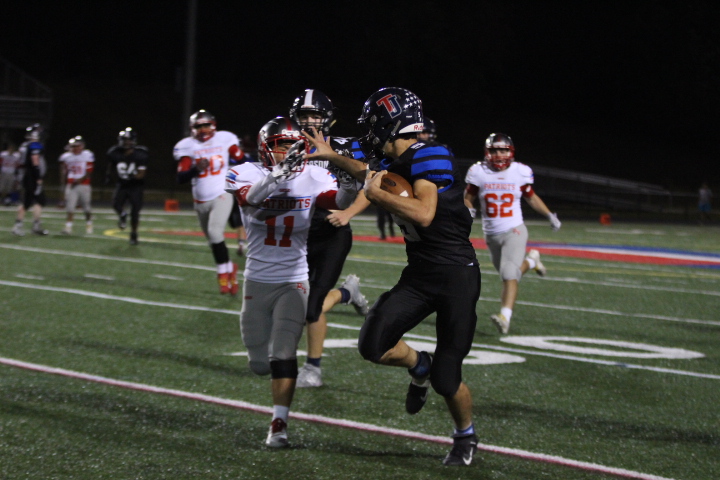 Stiff arming a defender, running back Niko Economos (5) charges towards the end-zone
