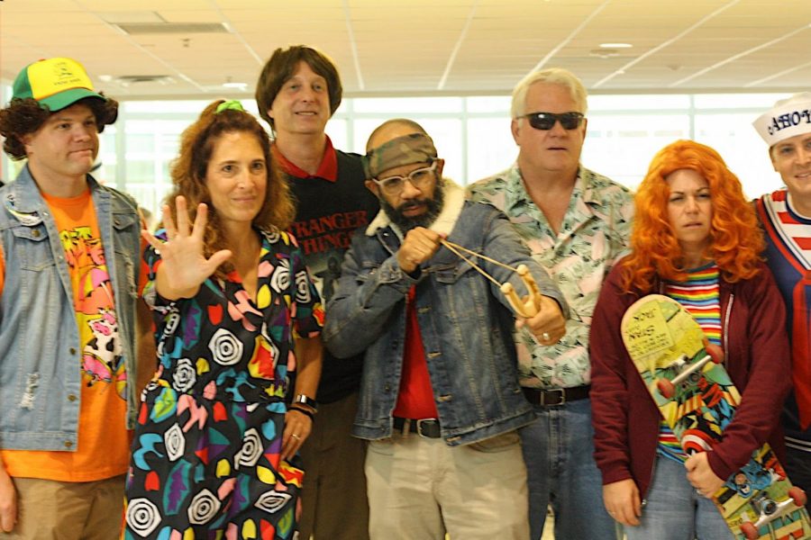 Posing for a picture after having finished conducting the Halloween contest, teachers, from left to right, Mr. Kosatka, Dr. Bonitatibus, Mr. Yohe, Mr. Frank, Mr. Hodges, Ms. Hawkins, and Mr. Resquin, are dressed up as the Stranger Things cast. Representing the characters with their funky patterned 90s clothing, they strike adolescent-like poses.