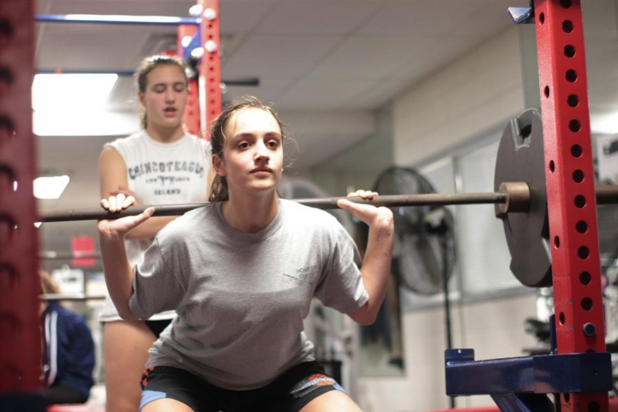 Junior Sarabeth Joyner lifts a dumbbell in the Jefferson weight room while sophomore Alexandra Fall spots and encourages her. The basketball players are mid-conditioning, where they exercise to build muscle and stamina. “Conditioning days [are] fun because youre sore the day after and it feels really good,” freshman Aditi Shukla said. 
