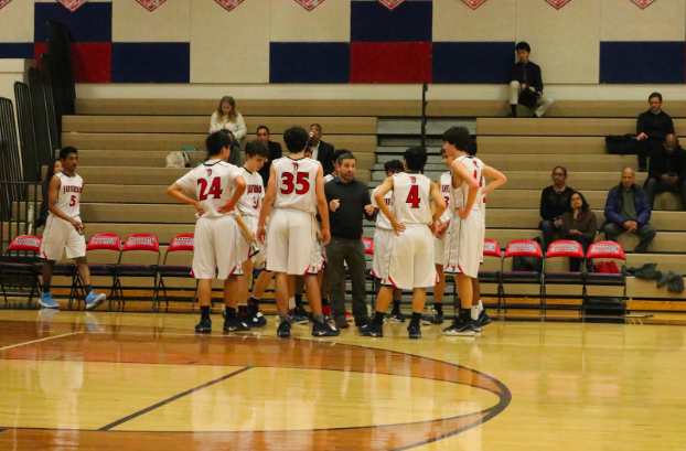 The team huddles up as the coach gives his insight at the end of the first quarter. The team had a strong start and they hope to maintain their lead.
