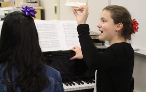 Reading from sheet music, sophomore Micaela Wells vocalizes with other members of Jefferson's Madrigals group 