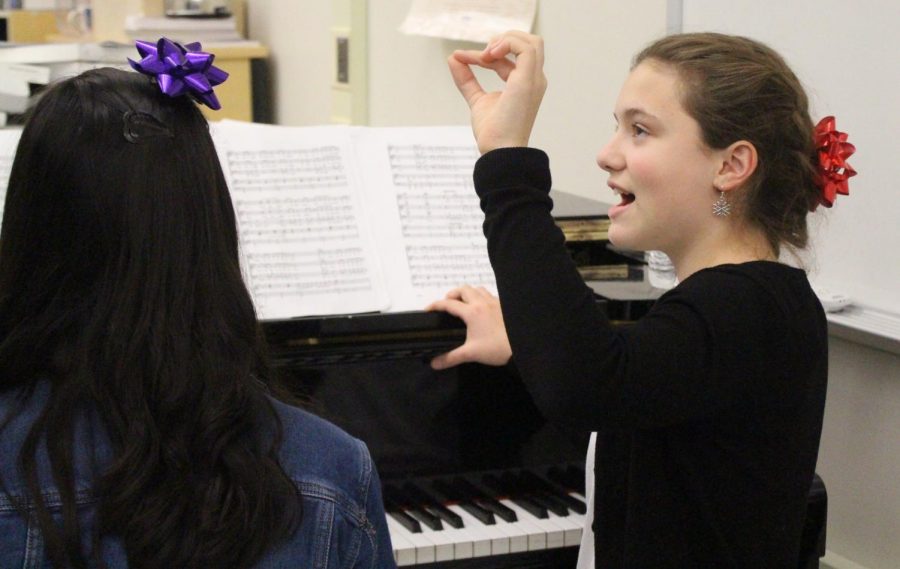 Reading from sheet music, sophomore Micaela Wells vocalizes with other members of Jefferson's Madrigals group 