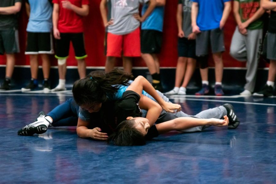 Sparring in practice, junior Brianna Ta wrestles freshman Nick Ta to the ground 