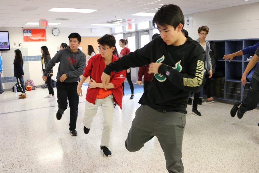 In unision with two other students, senior Jae Canneti practices a move from Urban Dance Movement's iNite act