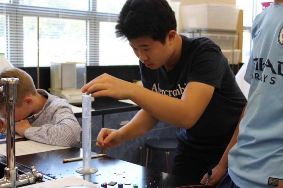 While conducting a density lab in chemistry, sophomore Bowen Zhang drops an object into a graduated cylinder filled with water.