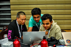 Jefferson CS instructor and HackTJ mentor Dan Tra watches as sophomores Harshavardhan Harish (left) and Umang Jain (right) run their code at the 2019 HackTJ 6.0.
