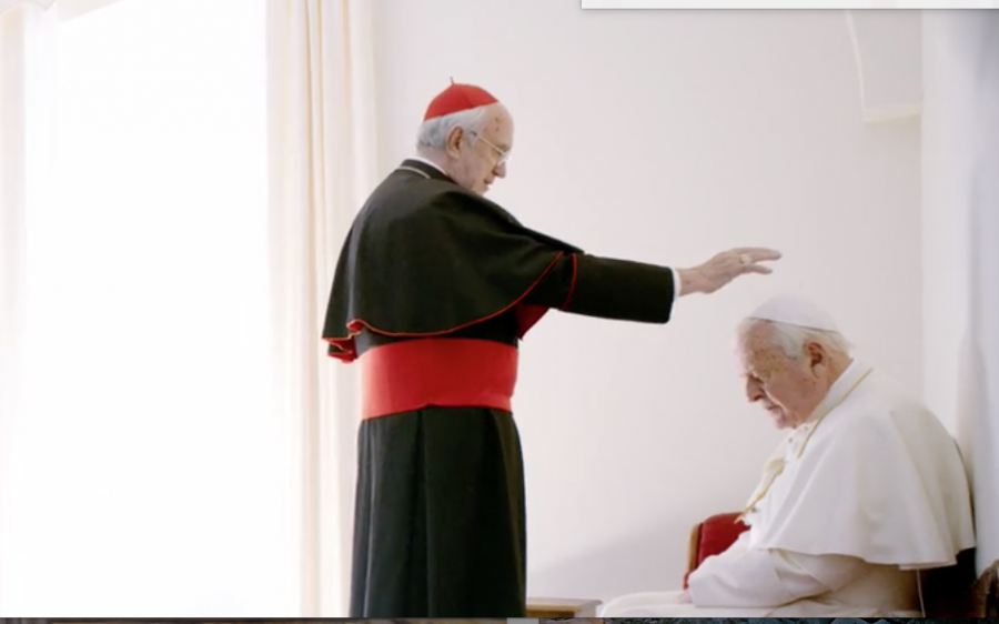 Cardinale Bergoglio (Jonathan Pryce) stands before a kneeling Pope Benedict (Anthony Hopkins) after the Pope Benedict offered him his title of 