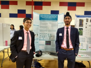 Smiling, juniors Divjot Bedi and Rishabh Misra stand by their science fair board