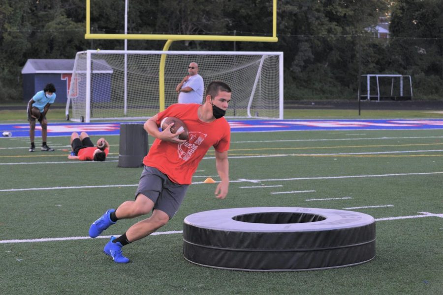 Weaving his way around obstacles, junior Hilal Hussain participates in a running back drill. Players are now allowed to use footballs, but they must be disinfected regularly. “It [felt] like a normal practice, which was a nice refresher from all the quarantine,” Hussain said.
