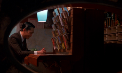 Mr. Chow (Tony Leung) is framed within a mirror and a wall to keep him trapped. Image courtesy of [FILMGRAB].