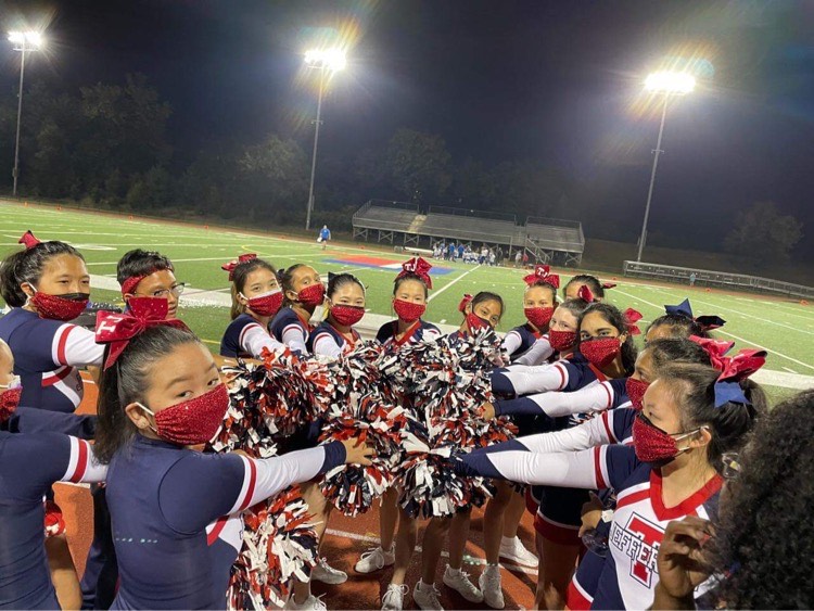 The TJHSST cheer team practices together on the football field.