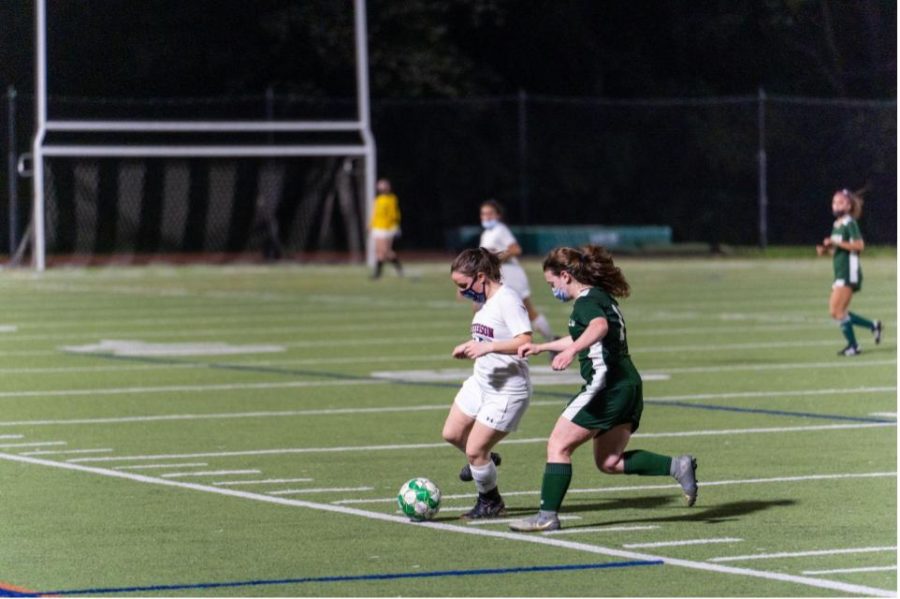 Senior Lauren Delwiche guards the ball, wearing a mask to follow COVID protocol. Now that vaccines are available and students are returning to in person schooling, FCPS has updated the rules. 