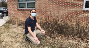 Liam Carey kneels in front of a plot of dead plants outside of Jefferson. Carey founded this as a wildflower garden due to his interest in gardening, but these flowers do not survive in the winter. Its a bit dead right now, but itll grow back in the spring, Carey said.