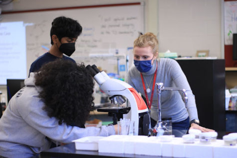  Biology teacher Dr. Morrow helps two students with their Biology labs. “My past experience definitely helps me help my students during class,” Morrow said.  