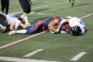 Senior running back Christian Min (2) is tackled after a 10-yard carry in the third quarter. In the second half, despite a constant back-and-forth, the Colonials were unable to score. “We’re a good team. It all comes down to how much effort we’re going to put in [and] how focused we decide we’re going to be,” Min said.