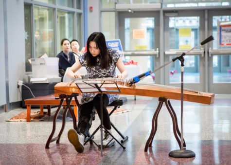 Plucking the zither strings, senior Tiffany Lee plays classical Chinese music. “I’ve never learned how to play Chinese zither, but it looks really cool,” Freshman Olivia Wu said. “When one of my friends heard Tiffany play the first song, they said their mom always sings that, so I thought that was a nice connection.”