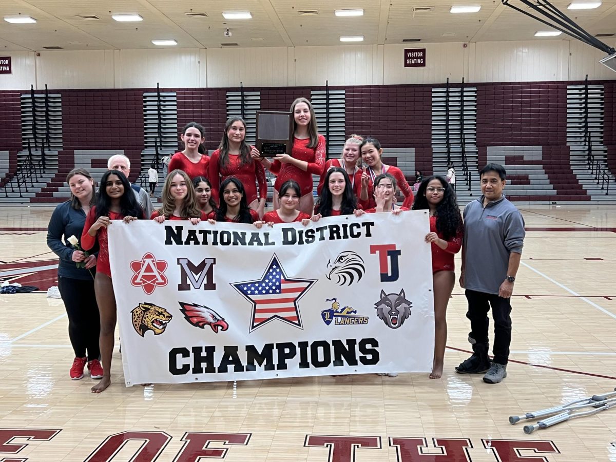 Holding up the hard-earned National District Championships banner, Jefferson’s gymnastics team poses for a picture. “We wanted to win districts for our senior captain, Lauren, so it was also very meaningful that we won this year. We bid her off with that and it was super cute,” freshman Aerin Bernstein said.
