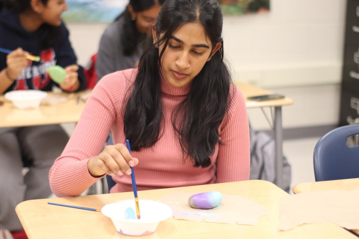 Freshman Maya John cleans her paintbrush in water during TJ Give's first ever kindness rock painting event. "Some that used to happen around a lot of Virginia was people painting kind and wholesome messages on rocks and the road," Lina Raymond said. "I also remember that when I graduated sixth grade in elementary school, they had us all paint rocks and leave them in the front of the school. A lot of them are still there. It was a really nice touch and felt like we were leaving a little part of ourselves."