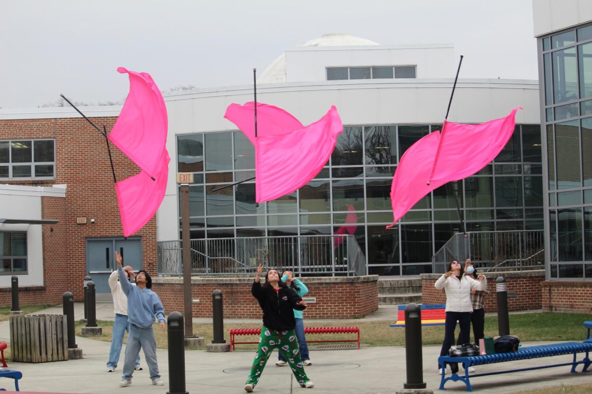 Members of the color guard practice with their flags during a color guard 8th period. “In the fall, you have to be more versatile,” senior assistant color guard captain Gwyneth Moreno said. “There’s definitely a lot more running around and [you have] to be aware of different instruments and learn music. It’s a more militaristic kind of way we rehearse. In the winter, you’re able to do harder tosses because you don’t have to adjust to any wind.”