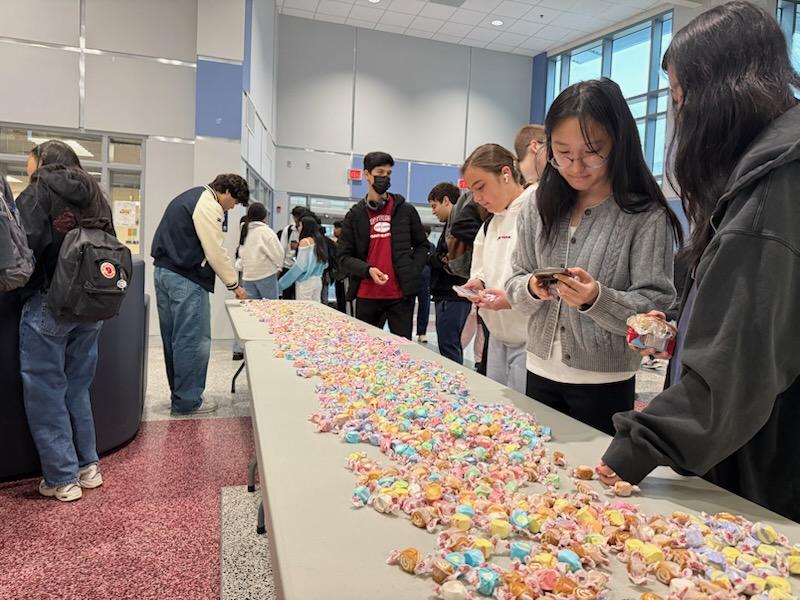 Students take taffy from the tables in Nobel Commons. “Get the word out and let everyone know,” principal Michael Mukai said. “We want to share this moment before we go away [for spring break].” 