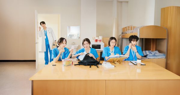 The four first-year residents sit at a desk, showcasing their unique personalities in the series.