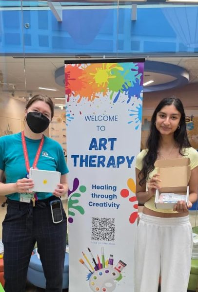 Art therapist Katherine Pedrick and senior Viola Pande pose for a picture in front of the art therapy banner at the Children’s National Hospital’s annual Sunflower Festival, where Pande distributed the art kits that she made for her Gold Award. “Art is so multifaceted,” Pande said. “Even though I'm doing physical art— and I think physical art is really therapeutic because you are painting or coloring—art can come in many different forms. I’m combining music and physical art in [my Gold Award]. Music has been a really helpful form of therapy for me throughout my high school years and throughout my life in general because I can pour my energy into something that's not school. It’s also creating something [that isn’t] physical or visual.”