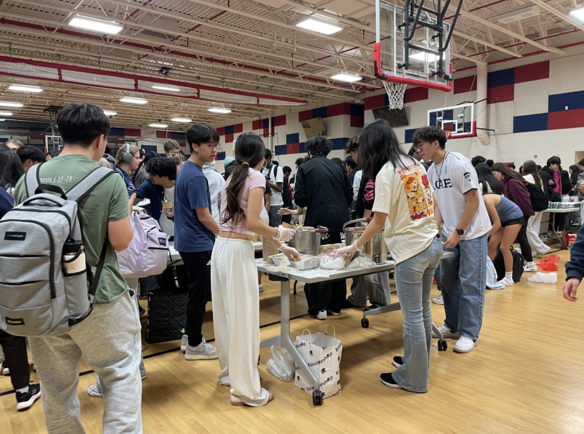 Korean Culture Club students help sell food items at a booth. “I helped out with the ethics ball booth, so I helped with organizing the money and handing out churros,” freshman Meera Bansal said.